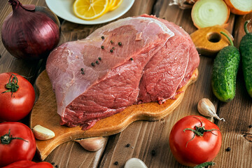 Big piece of fresh raw beef with vegetables on the wooden table