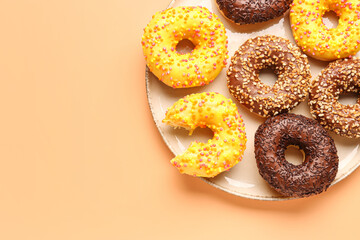 Plate with sweet donuts on beige background