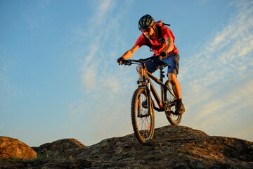 Cyclist in Red T-Shirt Riding the Bike Down the Rock on the Blue Sky Background. Extreme Sport and...