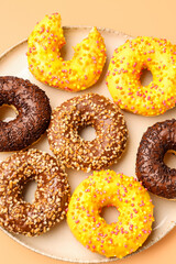 Plate with sweet donuts on beige background