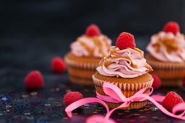 Delicious raspberry and caramel cupcakes on dark background