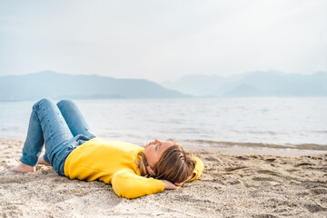 Lonely beautiful sad girl teenager lying thoughtfully on sand sea beach. Dreams,anxiety,worries about future,school friends,parents. Teen bullying, psychological problems in adolescent puberty period