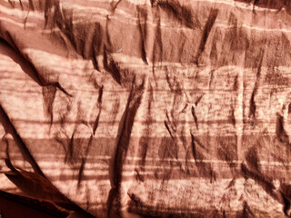 Abstract background and texture of crumpled brown satin fabric. Texture, pattern, frame, copy space