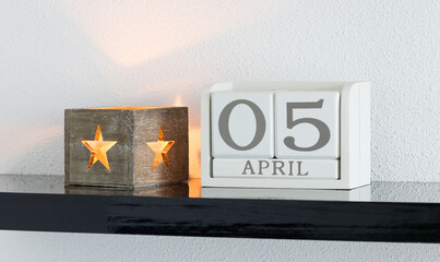 White block calendar present date 5 and month April on white wall background