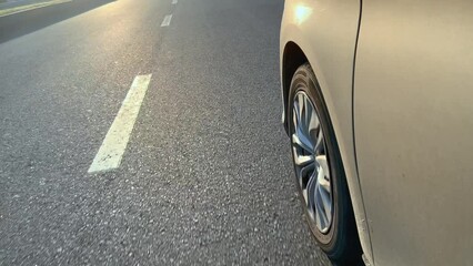 The wheel of the car while driving on an asphalt road.