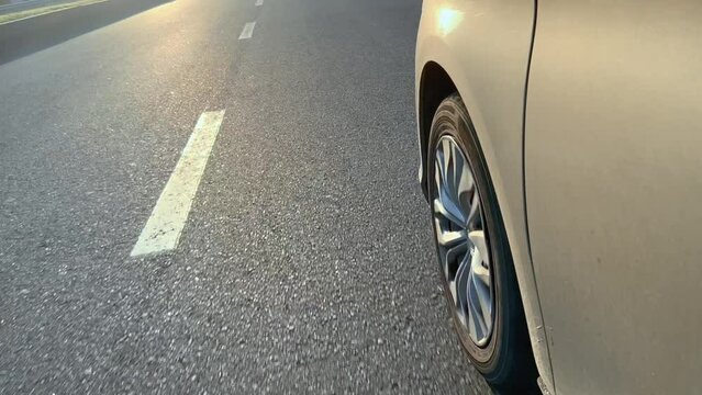 The wheel of the car while driving on an asphalt road.