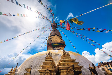 Nepal. Golden Stupa Bouddanath in Kathmandu with colorful Tibetan prayer flags, close-up on a sunny day. Was built in the 14th century. Blue cloudy sky in the background. Travel, holidays, sight - obrazy, fototapety, plakaty