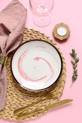Beautiful table setting with candle and branch on pink background