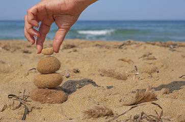 A hand balances ocean balls of posidonia seaweed on the beach. Inspirational summer landscape. Spa or wellness, freedom and stability and balance concept.