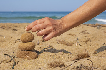 A hand balances ocean balls of posidonia seaweed on the beach. Inspirational summer landscape. Spa or wellness, freedom and stability and balance concept.