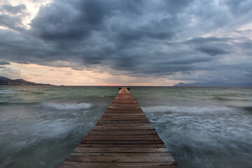 Dramatic Looking Morning at the Sea in Spain on Pier / Jetty - Majorca. Dark Clouds Before the Storm. Big Waves