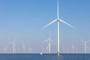Offshore wind farm with many windmills, the Netherlands with sailboat