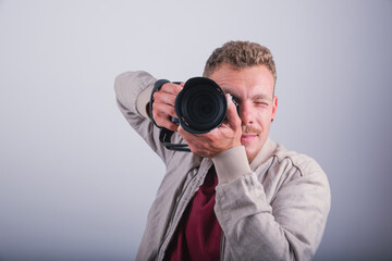 A photographer takes a photograph with his DSLR, studio shot with a white background