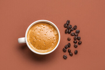 Cup of hot espresso and coffee beans on brown background