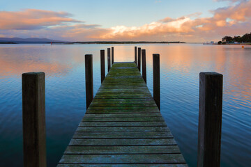 Fototapeta na wymiar Old timber jetty with green mossy planks in the sunset
