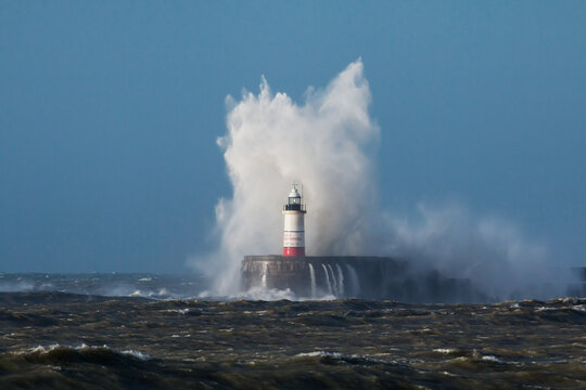 Breaking wave over Newhaven Lighthouse in East Sussex and rough sea.