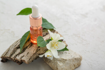 Bottle of cosmetic oil with jasmine flowers and tree bark on white background