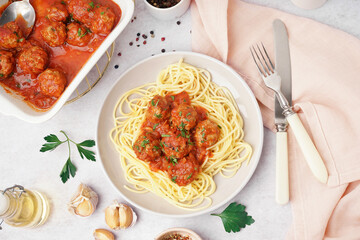 Plate of boiled pasta with tomato sauce and meat balls on white table