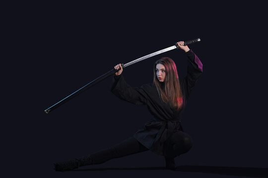 Beautiful sexy young woman with katana on dark background