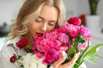 Young woman with peony flowers in kitchen, closeup