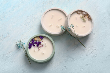 Holders with candles and flowers on blue background
