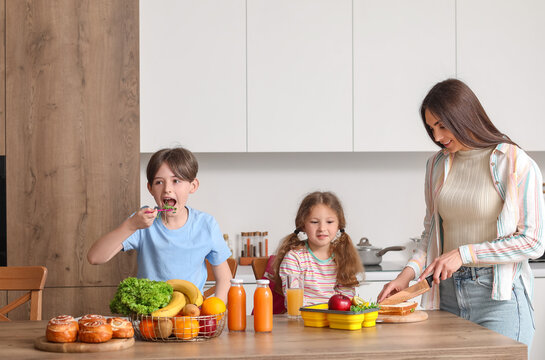 Mother preparing school lunch for her little children in kitchen