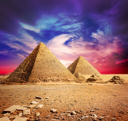 Fototapeta na wymiar Pyramids in desert under ultra violet clouds