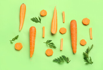 Fresh carrots and slices on green background