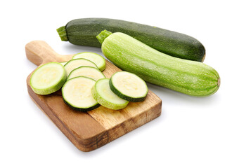Board with slices of fresh green zucchini on white background