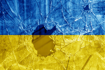 Bullet hole, cracks in the glass on a yellow-blue background. Ukraine flag on broken glass texture....