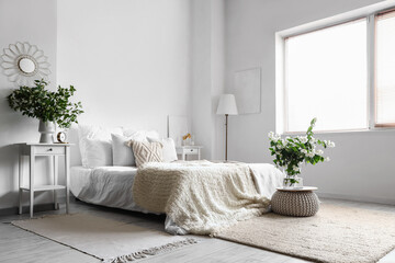 Interior of light bedroom decorated with blooming jasmine flowers in vase