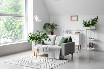 Grey sofa and vase with blooming jasmine flowers on coffee table in living room