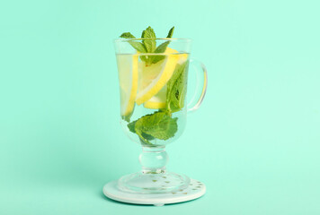 Fototapeta premium Glass of infused water with lemon and mint on turquoise background