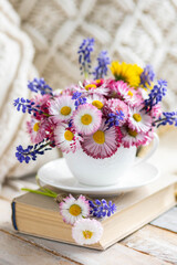 Countryside decor, old book, wooden background, straw hat. Greeting postcard with bright summer or spring flowers in a cute cup. Congratulations for Mother's or Women's day, birthday or anniversary