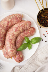Plate with raw homemade sausages on light background