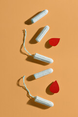 Composition with menstrual tampons and blood drops made of paper on beige background