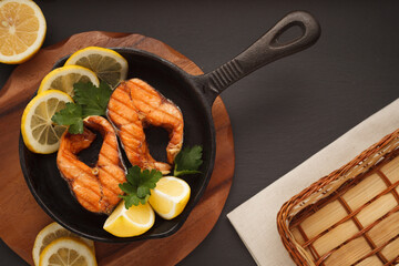 Fried or grilled salmon fillet on cast-iron pan with bread and lemon. Flatlay