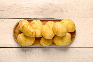 Tray with raw baby potatoes on white wooden background