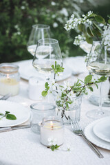 Rustic zero waste wedding decor with natural elements. Fresh spring blooming flowers, candles, linen napkins, wine glasses. Eco friendly decoration for the special holiday dinner. Romantic cozy place