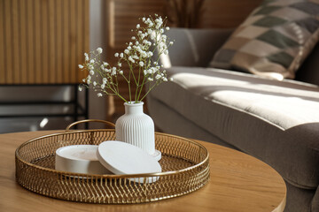 Tray with white candle and gypsophila flowers on table in living room, closeup