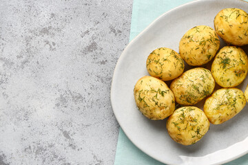 Plate of boiled baby potatoes with dill on grey background