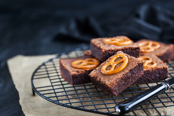 Homemade chocolate brownies with salted pretzels on top, close up, dark background