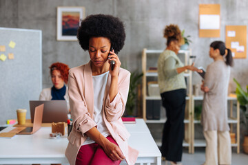 African-American business woman looking down while having unpleasant conversation over phone.