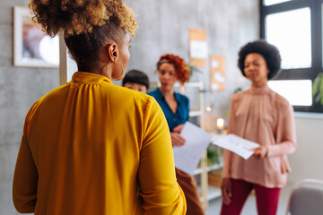 Rare view of African-American business woman talking with team members in office.