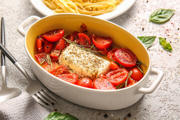 Baking dish with tomatoes and feta cheese on grey background