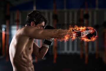 Fototapeta na wymiar Determined and confident boxer with fiery boxing gloves