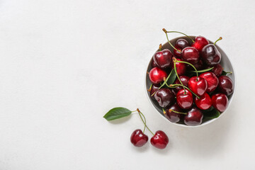 Bowl with sweet cherries on white background