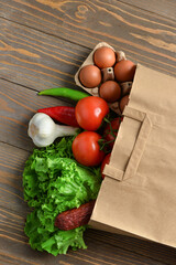 Paper bag with different products on wooden background