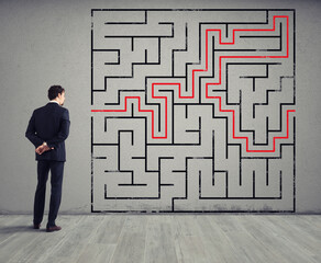 Businessman draws the solution of a complex labyrinth. Concept of problem solving