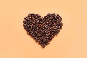 Heart made of coffee beans on orange background
